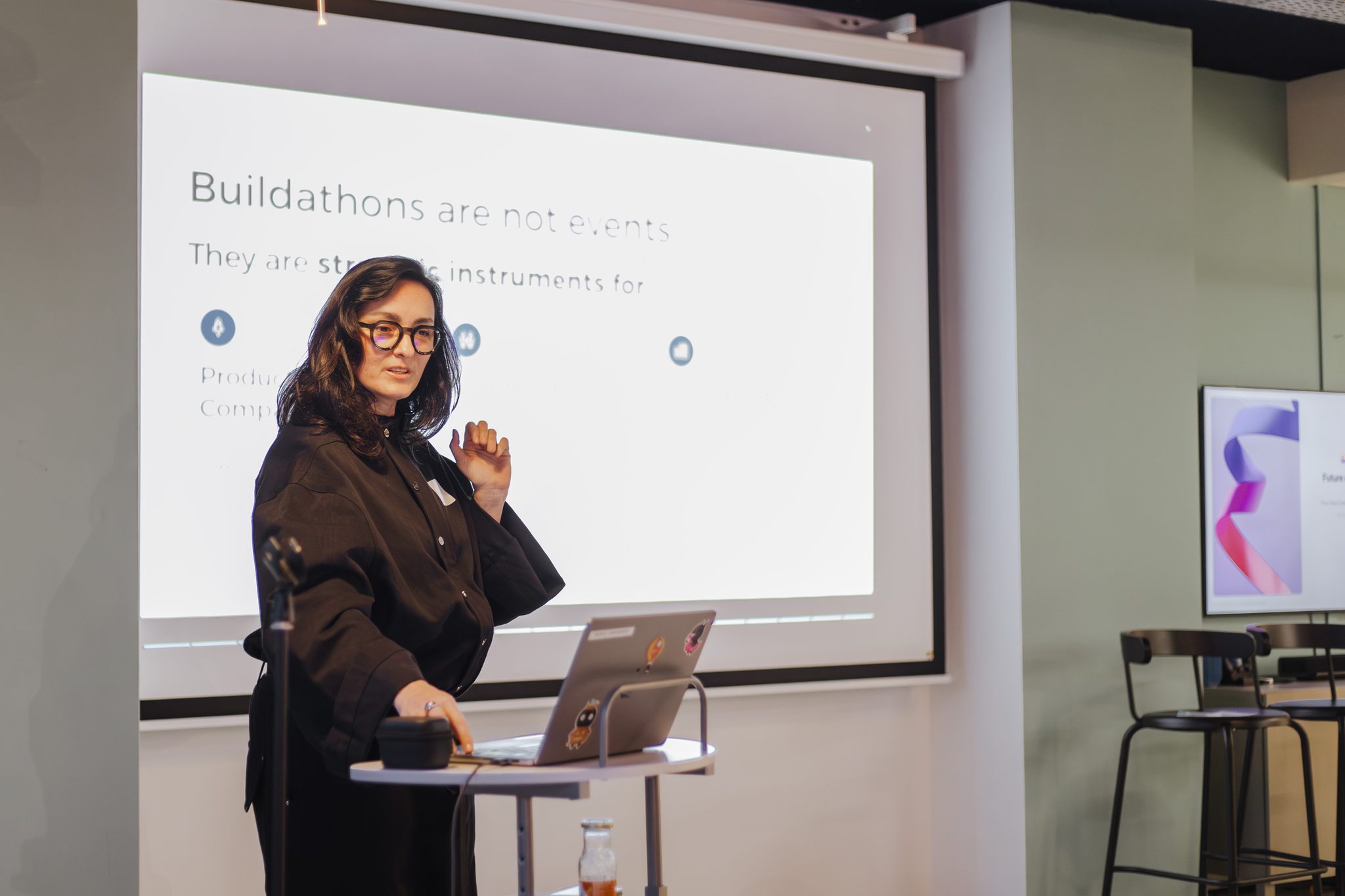 A presenter speaking in front of a buildathon strategy slide during the Amplitude community event in Amsterdam.