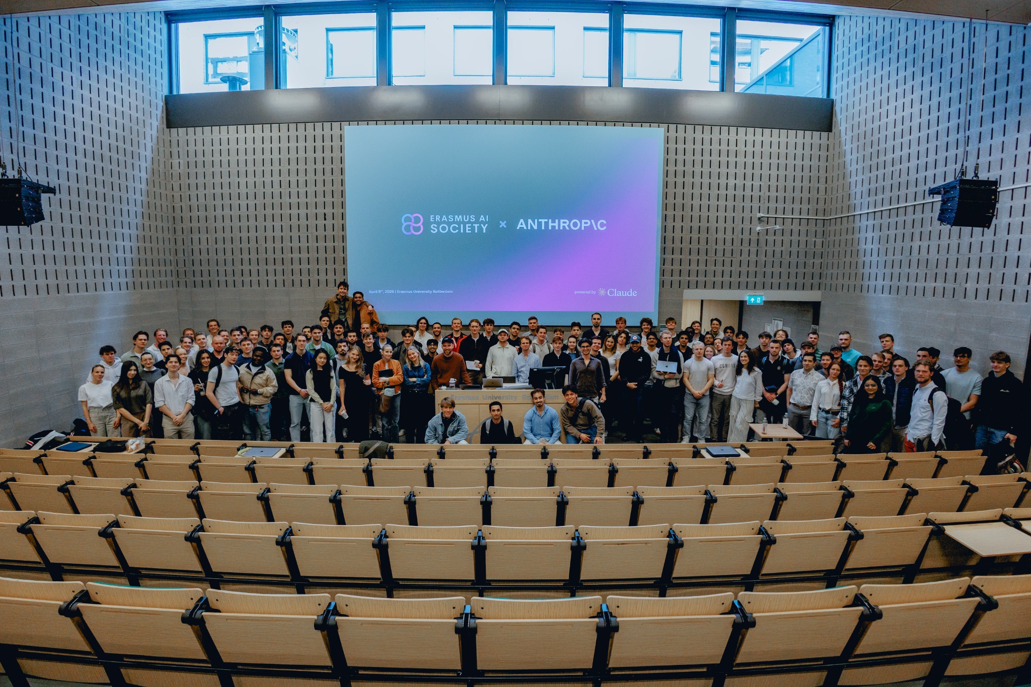 Student hackathon participants gathered in an auditorium beneath an Erasmus AI Society and Anthropic screen.