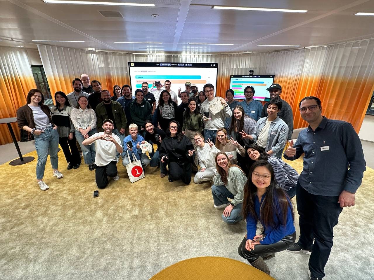 Buildathon participants posing together in front of Miro collaboration screens in Amsterdam.